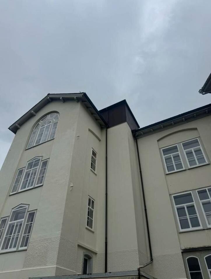 Mehrstöckiges Wohnhaus mit Turm und frisch gestrichener heller Fassade